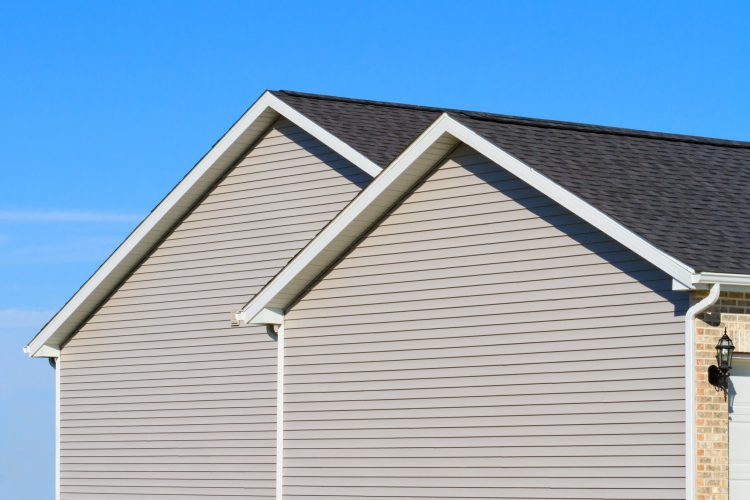 Side view of new one story home showing new vinyl siding and asphalt roof with blue sky in the background